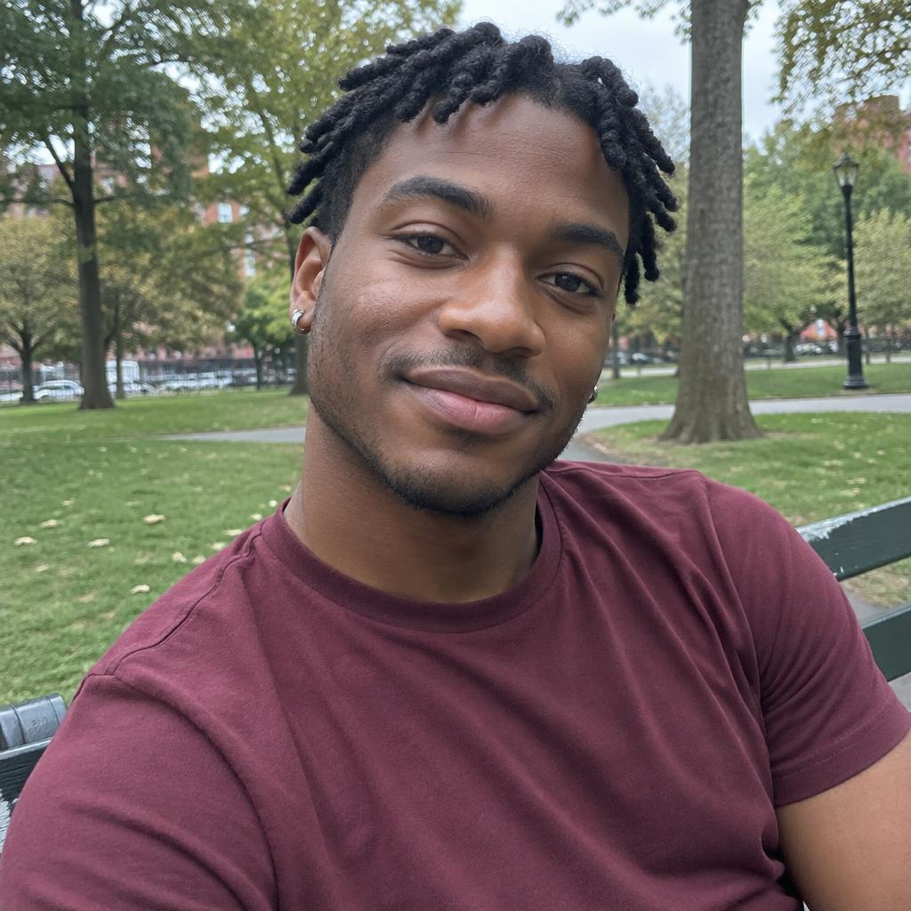 Young adult with short twists and a burgundy T-shirt relaxing on a park bench